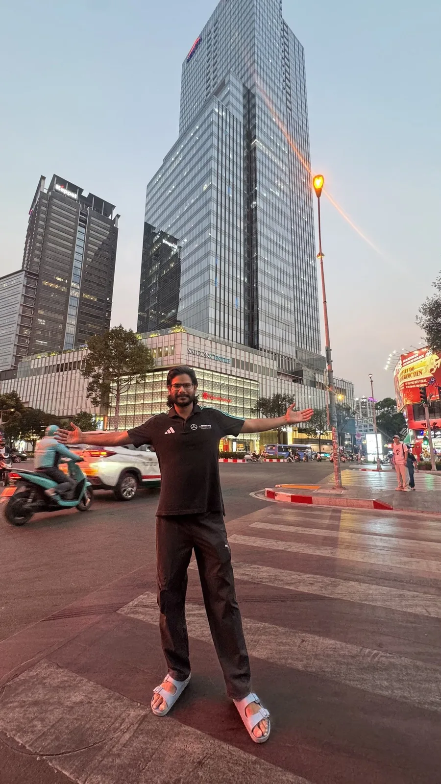Gautam Kumawat on a city street at dusk, towers and moving traffic behind him