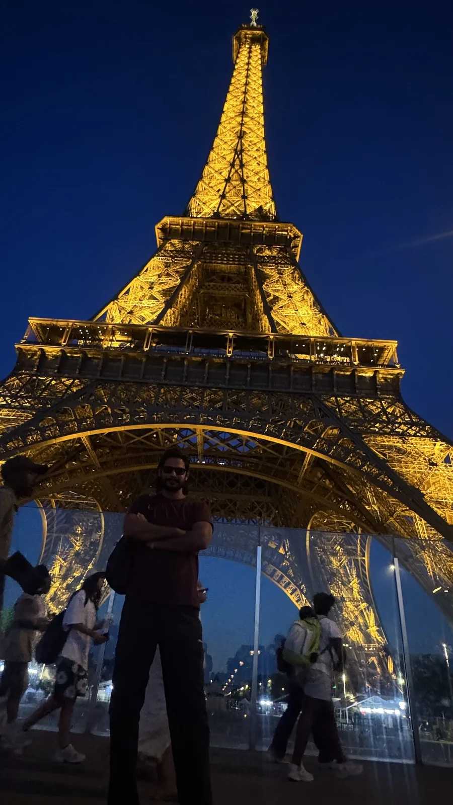 Gautam Kumawat beneath the Eiffel Tower, lit gold against a night sky