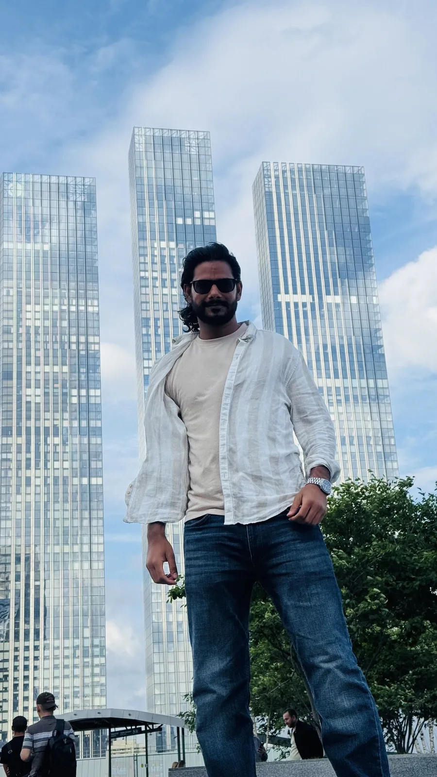 Gautam Kumawat in front of a cluster of glass skyscrapers rising into haze